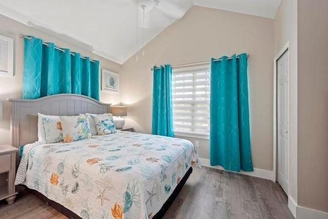 bedroom featuring ceiling fan, wood-type flooring, a closet, and lofted ceiling