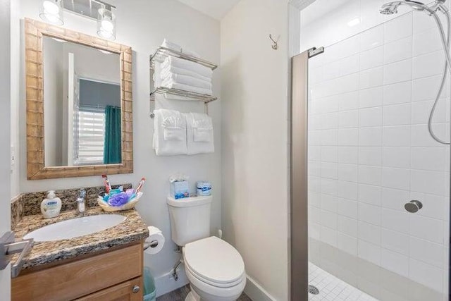 bathroom with toilet, vanity, and a tile shower