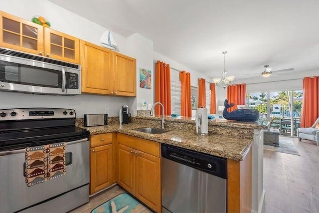 kitchen with kitchen peninsula, appliances with stainless steel finishes, sink, and light hardwood / wood-style flooring