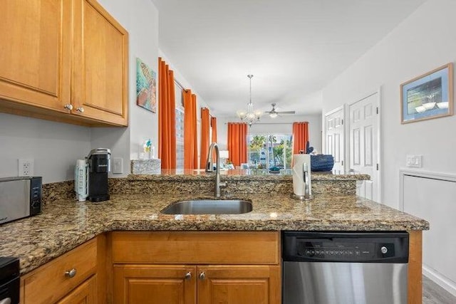 kitchen featuring ceiling fan with notable chandelier, dishwasher, sink, kitchen peninsula, and stone counters