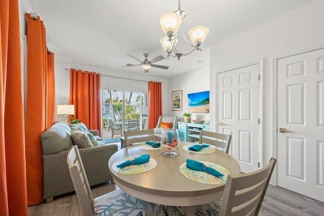 dining space featuring ceiling fan with notable chandelier and light hardwood / wood-style floors