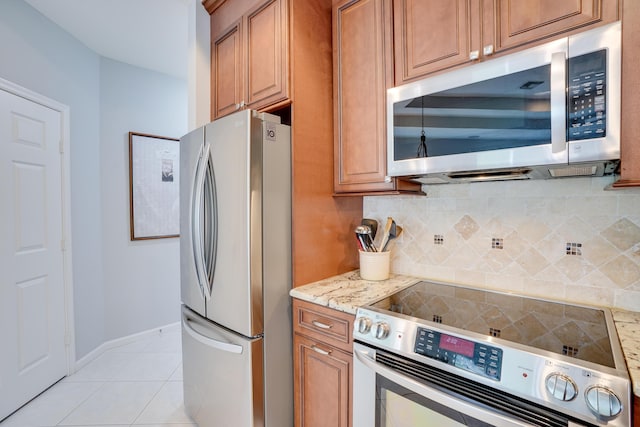 kitchen featuring decorative backsplash, stainless steel appliances, light stone counters, and light tile patterned flooring