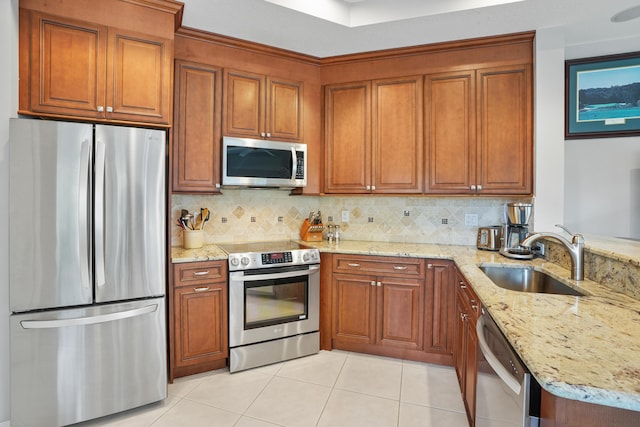 kitchen featuring backsplash, light stone countertops, sink, and stainless steel appliances