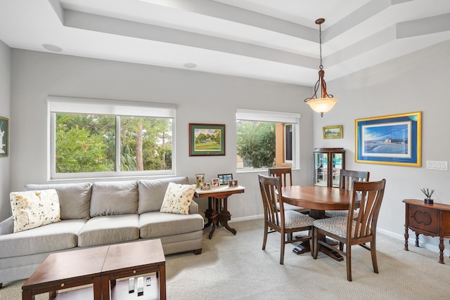 carpeted dining space with a wealth of natural light and a tray ceiling