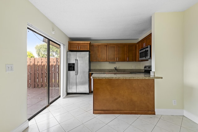 kitchen with a textured ceiling, sink, stainless steel appliances, and dark stone counters