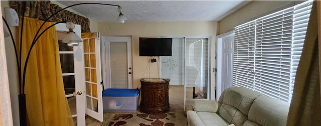 living area with french doors and a textured ceiling