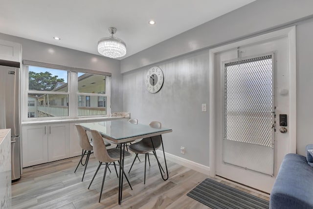 dining area with light hardwood / wood-style flooring and a notable chandelier