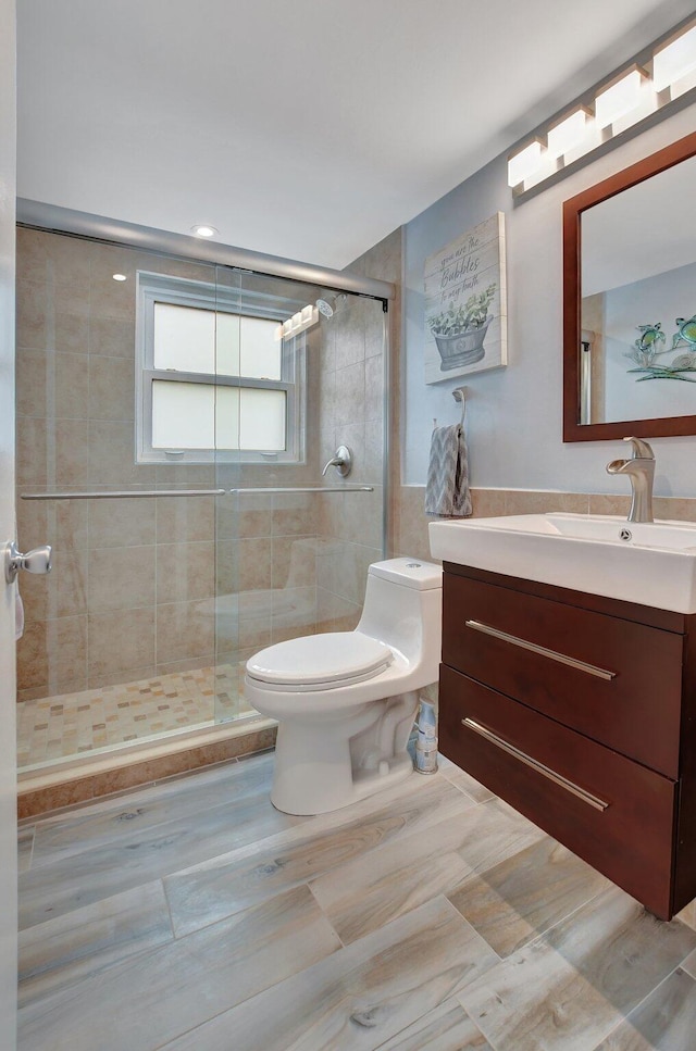 bathroom featuring vanity, a shower with shower door, and toilet