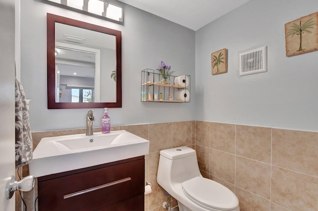 bathroom featuring vanity, toilet, and tile walls