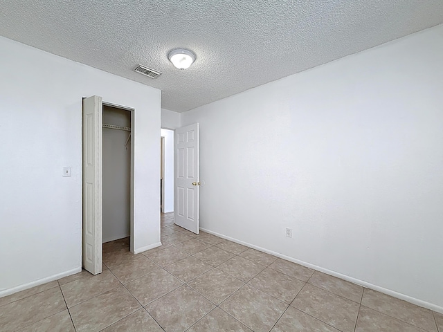 unfurnished bedroom featuring light tile patterned flooring, baseboards, visible vents, and a closet