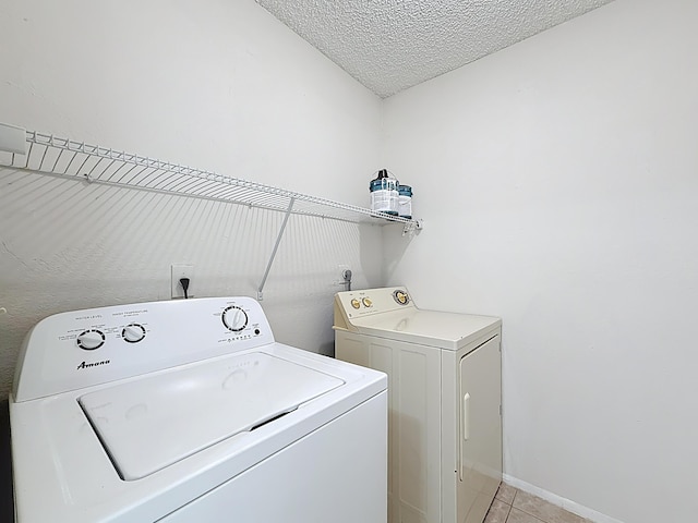 laundry room with washer and dryer, a textured ceiling, laundry area, and light tile patterned floors