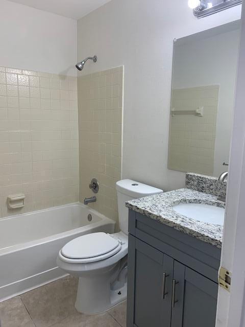 full bathroom with tile patterned floors, vanity, tiled shower / bath combo, and toilet