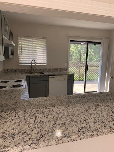 kitchen featuring dishwasher, range, light stone countertops, and sink