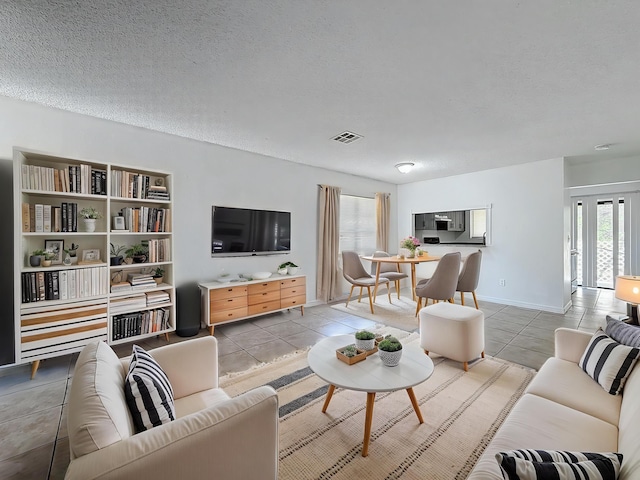 living area with a textured ceiling, light tile patterned flooring, and visible vents