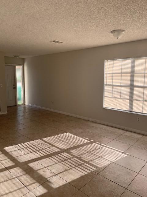 spare room featuring light tile patterned floors and a textured ceiling