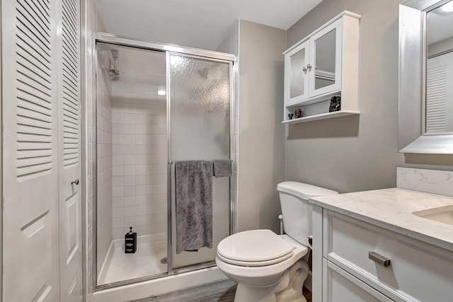 bathroom with an enclosed shower, vanity, toilet, and wood-type flooring