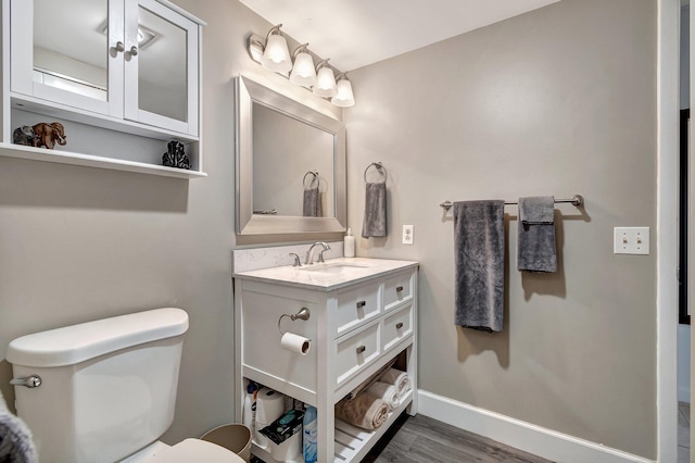 bathroom with toilet, vanity, and hardwood / wood-style flooring