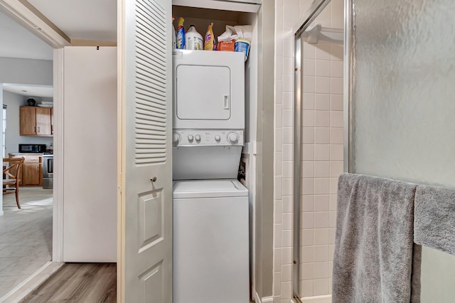 clothes washing area featuring stacked washer / dryer and light hardwood / wood-style flooring