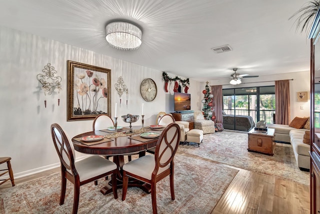 dining area featuring light hardwood / wood-style flooring and ceiling fan with notable chandelier