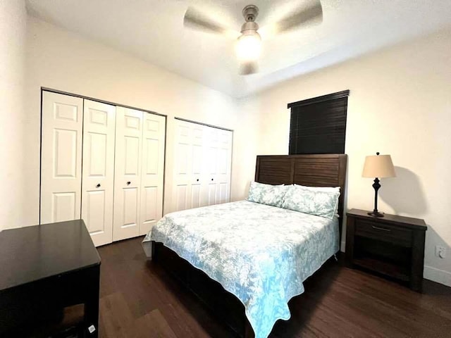 bedroom featuring multiple closets, ceiling fan, and dark wood-type flooring