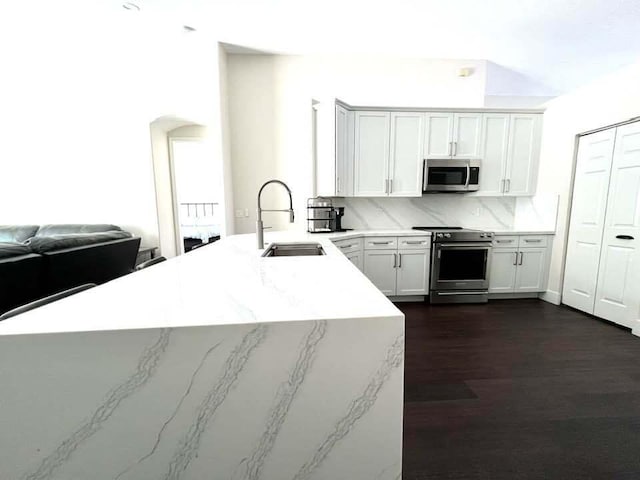 kitchen with white cabinets, sink, decorative backsplash, dark hardwood / wood-style flooring, and stainless steel appliances