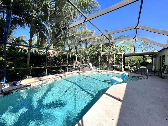 view of swimming pool with glass enclosure and a patio