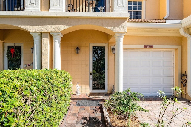 view of exterior entry featuring a balcony and a garage