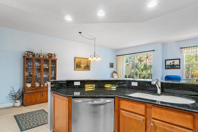 kitchen with dark stone countertops, a chandelier, sink, and stainless steel dishwasher