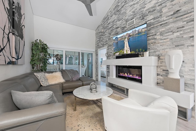 living room featuring a large fireplace, high vaulted ceiling, light hardwood / wood-style flooring, and ceiling fan