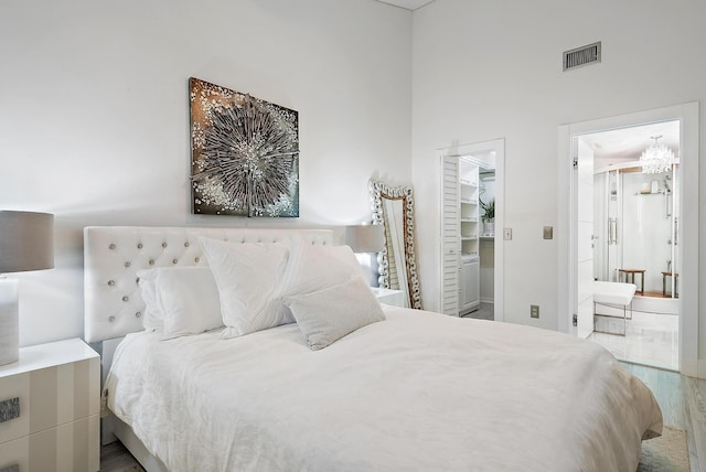 bedroom featuring a spacious closet, a closet, a towering ceiling, and wood-type flooring