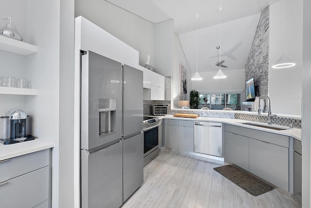 kitchen featuring appliances with stainless steel finishes, light wood-type flooring, gray cabinetry, sink, and pendant lighting