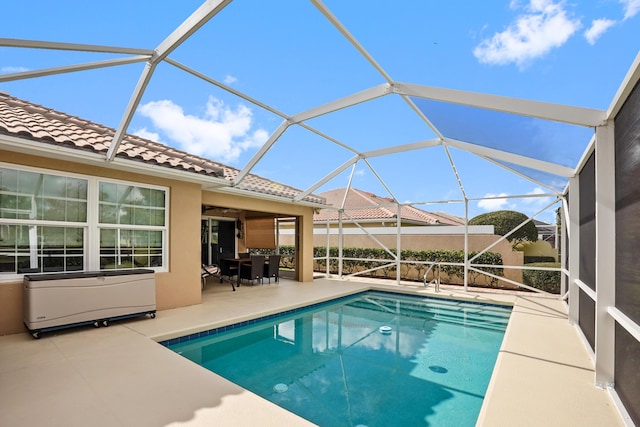 outdoor pool featuring glass enclosure and a patio area