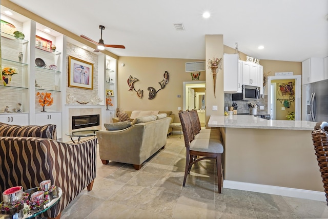 kitchen with white cabinets, built in features, appliances with stainless steel finishes, kitchen peninsula, and a breakfast bar area