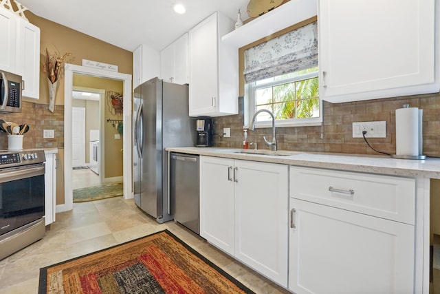 kitchen featuring backsplash, white cabinetry, sink, and appliances with stainless steel finishes