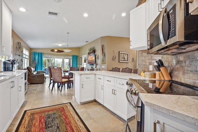 kitchen featuring white cabinetry, light stone countertops, stainless steel appliances, backsplash, and vaulted ceiling