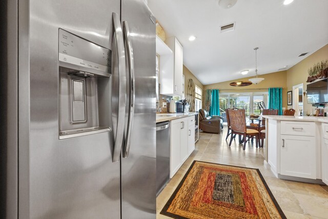 kitchen featuring decorative light fixtures, white cabinets, stainless steel appliances, and lofted ceiling