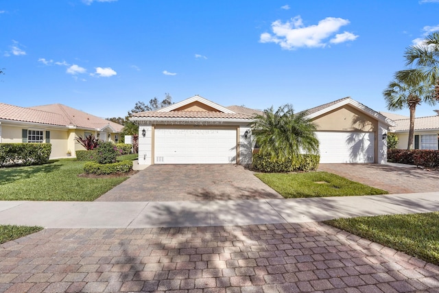 ranch-style house featuring stucco siding, a front lawn, decorative driveway, a garage, and a tiled roof