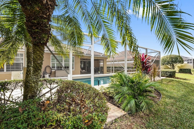 view of swimming pool featuring glass enclosure and a yard