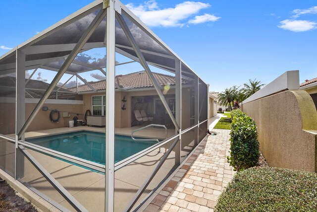 view of pool featuring glass enclosure and a patio