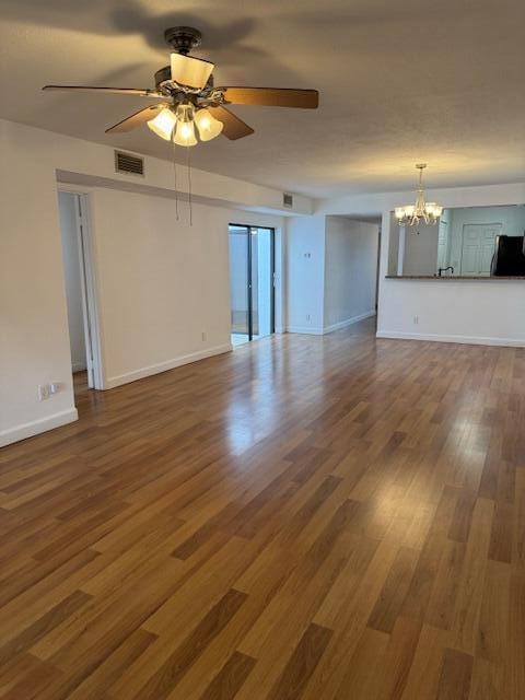 spare room featuring wood-type flooring and ceiling fan with notable chandelier