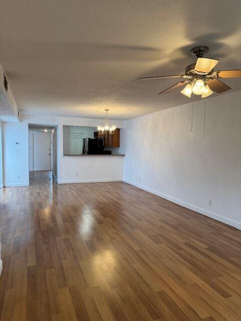 unfurnished living room featuring ceiling fan with notable chandelier and dark hardwood / wood-style flooring