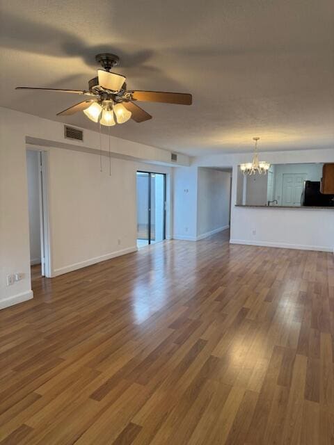 unfurnished living room featuring ceiling fan with notable chandelier and hardwood / wood-style flooring