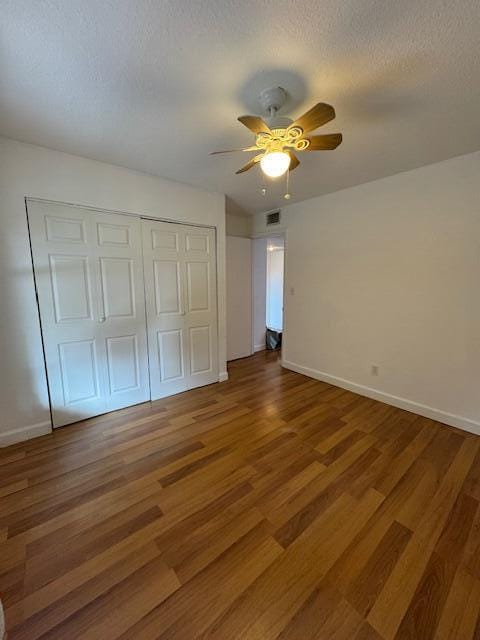 unfurnished bedroom with hardwood / wood-style floors, ceiling fan, a textured ceiling, and a closet