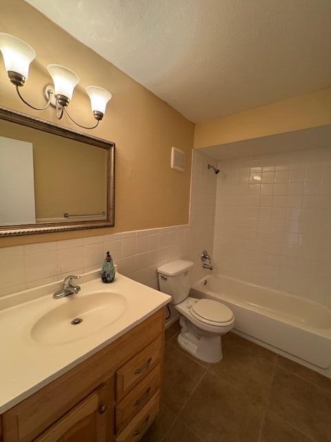 full bathroom featuring vanity, tile walls, tile patterned flooring, toilet, and tiled shower / bath