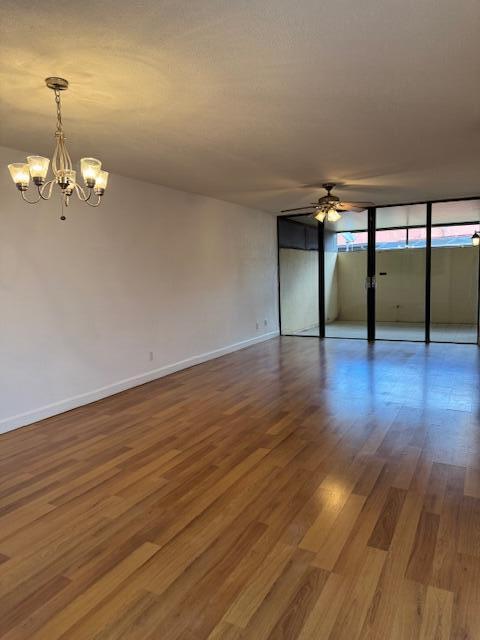 unfurnished room featuring hardwood / wood-style floors and ceiling fan with notable chandelier