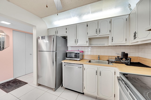 kitchen featuring decorative backsplash, light tile patterned flooring, sink, and appliances with stainless steel finishes