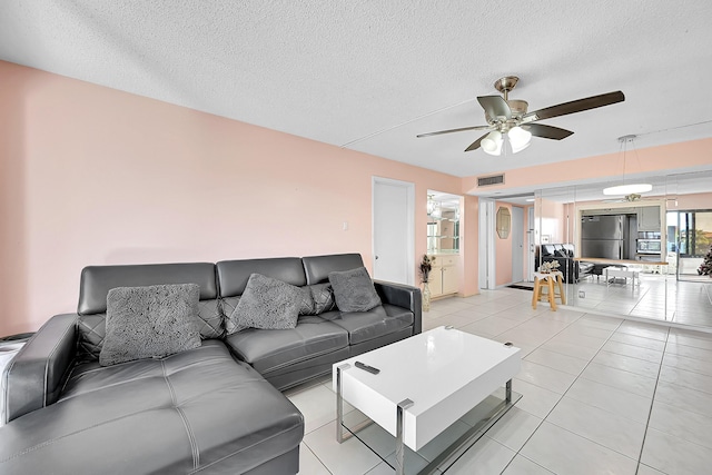 tiled living room with a textured ceiling and ceiling fan