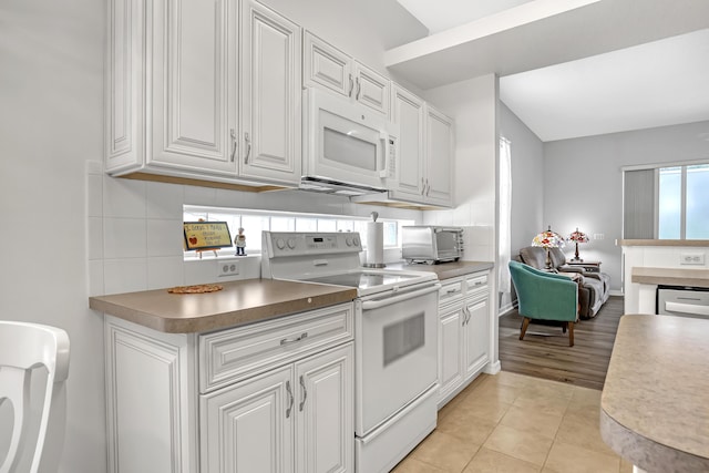 kitchen featuring tasteful backsplash, white appliances, and white cabinets