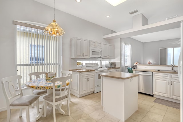 kitchen with decorative light fixtures, a kitchen island, white appliances, and white cabinetry