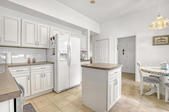 kitchen with tasteful backsplash, white fridge with ice dispenser, white cabinets, and pendant lighting